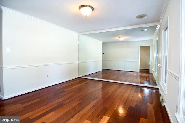 empty room with crown molding and dark wood-type flooring