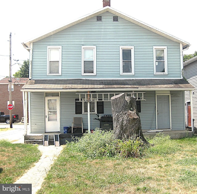 view of front facade featuring a porch and a chimney