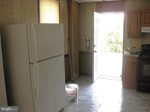 kitchen featuring a wealth of natural light, extractor fan, black range with electric stovetop, and white fridge