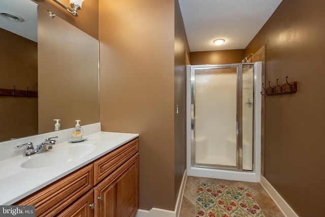 bathroom featuring vanity, a shower with shower door, a textured ceiling, and tile patterned floors