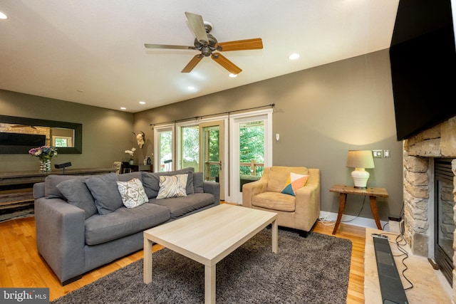 living room with light hardwood / wood-style floors, ceiling fan, and a fireplace