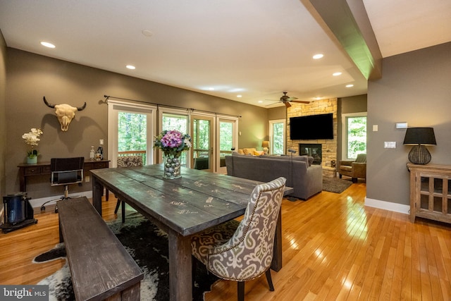 dining space featuring light hardwood / wood-style flooring, a wealth of natural light, ceiling fan, and a fireplace