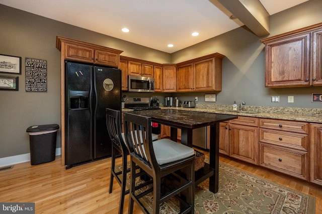 kitchen featuring light stone counters, light hardwood / wood-style floors, appliances with stainless steel finishes, and sink