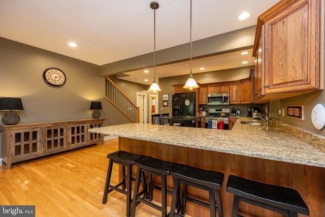 kitchen with a kitchen breakfast bar, kitchen peninsula, light hardwood / wood-style flooring, and stainless steel appliances