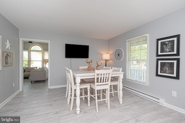 dining space featuring a healthy amount of sunlight, baseboard heating, and light hardwood / wood-style floors