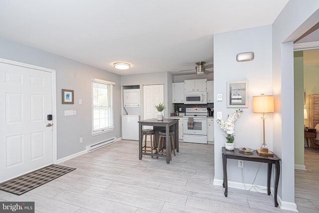 entryway featuring stacked washer and dryer, light hardwood / wood-style flooring, a baseboard radiator, and ceiling fan