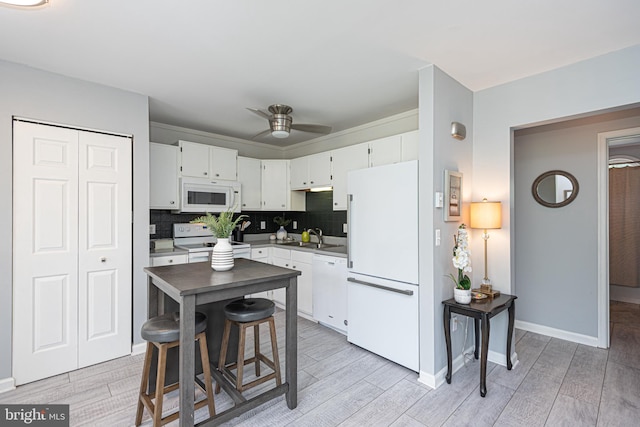 kitchen with white appliances, white cabinetry, and light hardwood / wood-style floors