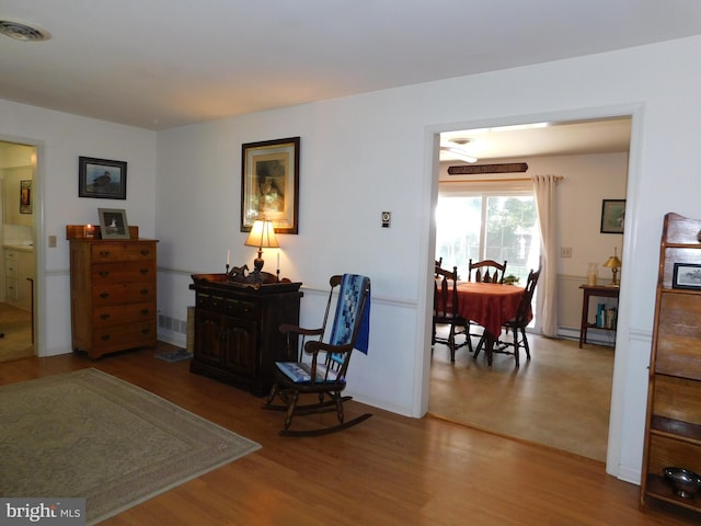 sitting room featuring wood-type flooring and a baseboard heating unit