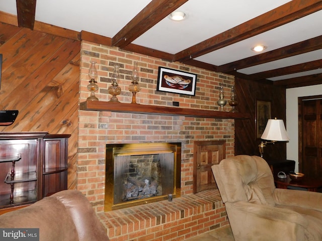 living room with wooden walls, a fireplace, and beam ceiling