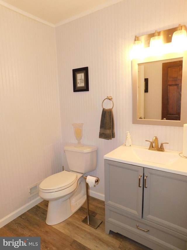 bathroom with wood-type flooring, vanity, crown molding, and toilet