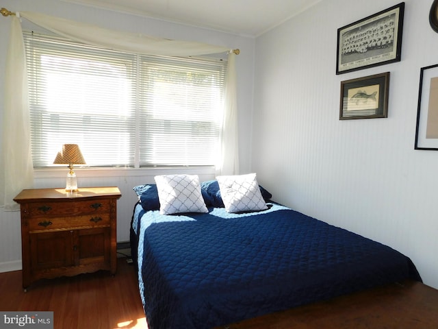 bedroom with crown molding and dark wood-type flooring