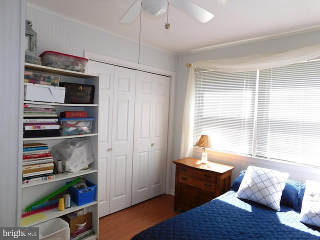 bedroom with a closet, ceiling fan, hardwood / wood-style flooring, and crown molding