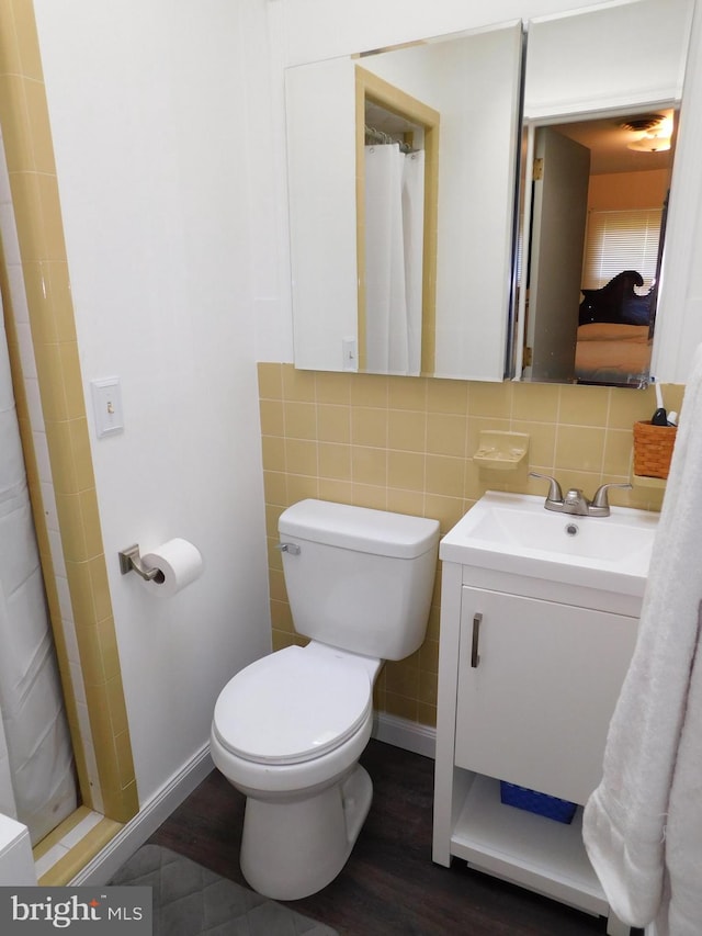 bathroom featuring tile walls, hardwood / wood-style flooring, a shower with shower curtain, vanity, and toilet