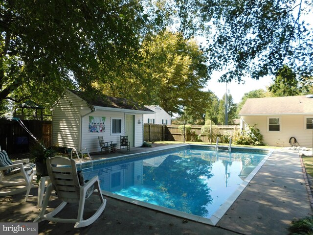 view of pool with a patio and an outbuilding