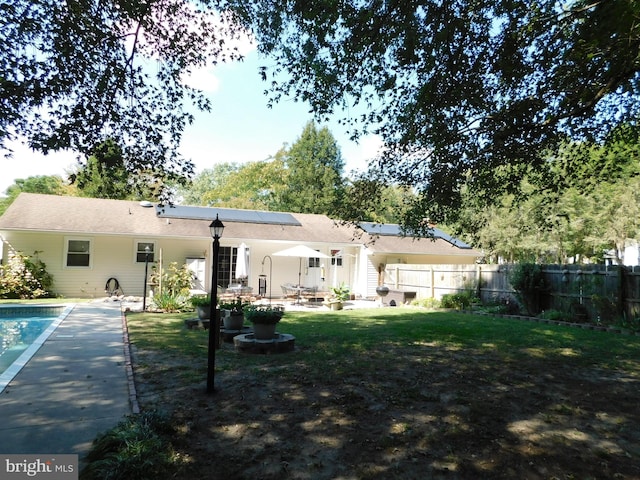 back of house featuring a fenced in pool, solar panels, and a patio