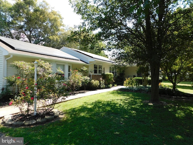 ranch-style home featuring a front lawn and solar panels