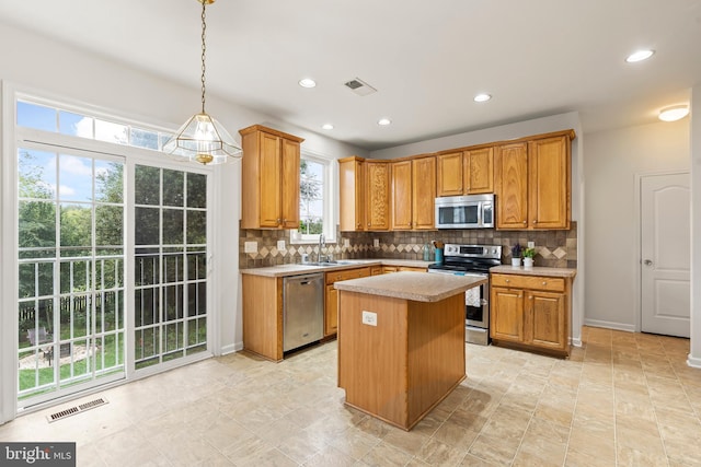 kitchen featuring appliances with stainless steel finishes, hanging light fixtures, decorative backsplash, and a center island