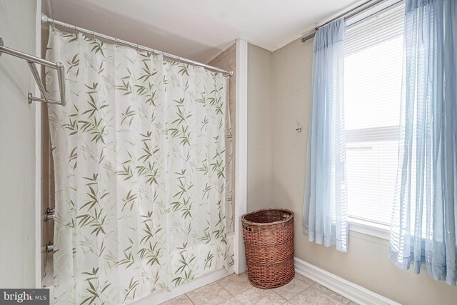 bathroom with a shower with shower curtain and tile patterned floors