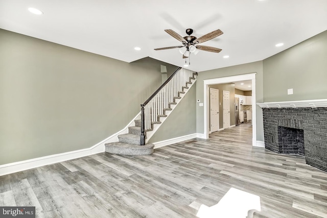 unfurnished living room with ceiling fan, light wood-type flooring, and a fireplace