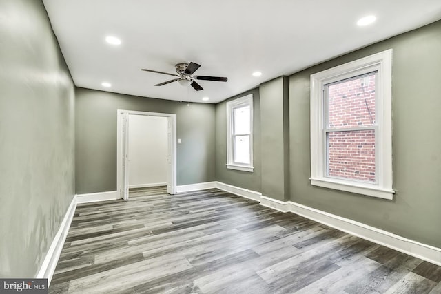 spare room with ceiling fan, a wealth of natural light, and wood-type flooring