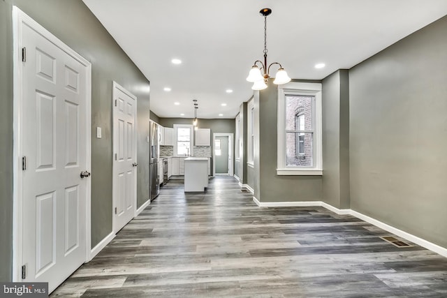 interior space featuring a wealth of natural light, a notable chandelier, and wood-type flooring