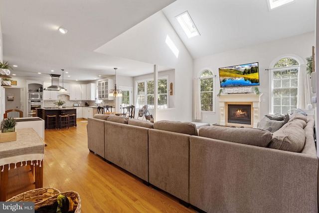 living room with a premium fireplace, plenty of natural light, lofted ceiling with skylight, and light hardwood / wood-style floors