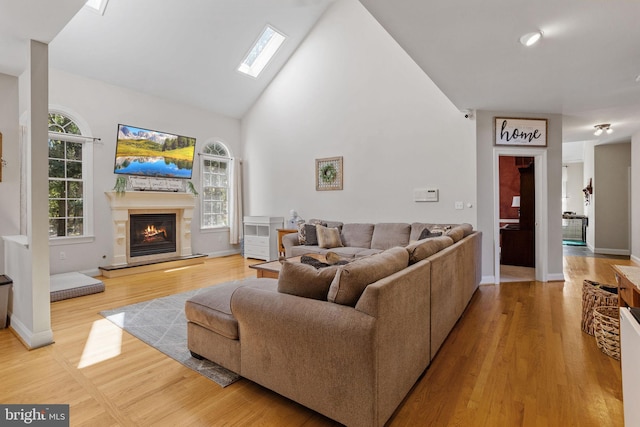 living room featuring light hardwood / wood-style flooring and vaulted ceiling with skylight