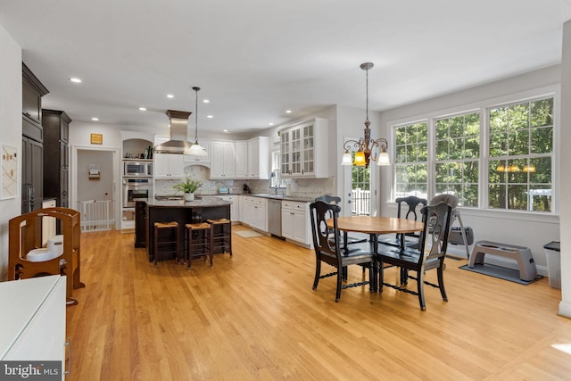 dining room featuring an inviting chandelier, sink, and light hardwood / wood-style floors