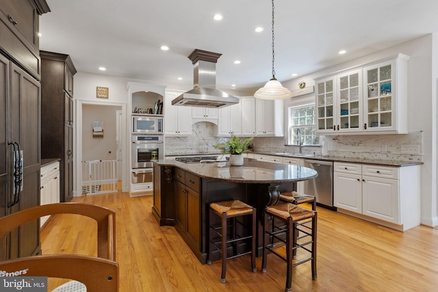 kitchen featuring a kitchen island, light stone countertops, light hardwood / wood-style flooring, island range hood, and stainless steel appliances