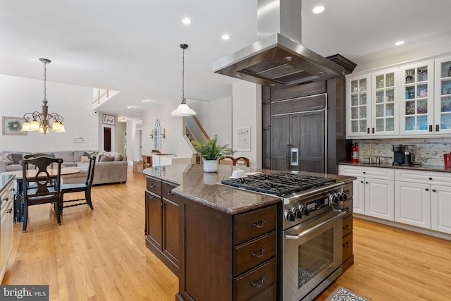 kitchen featuring light hardwood / wood-style flooring, white cabinetry, premium appliances, dark stone counters, and island exhaust hood