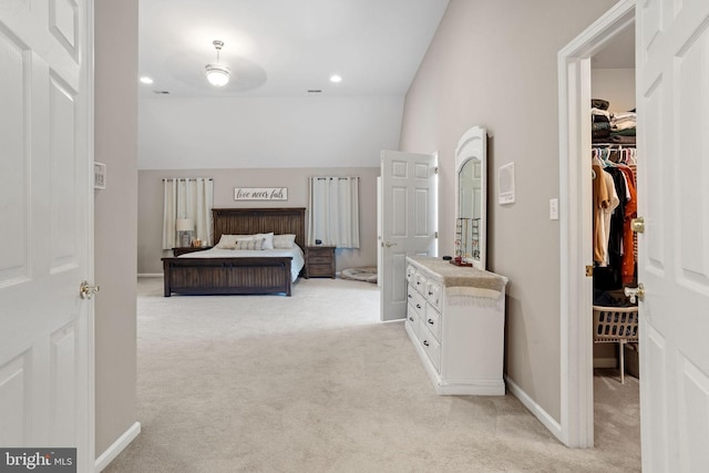 bedroom featuring vaulted ceiling, a walk in closet, and light colored carpet