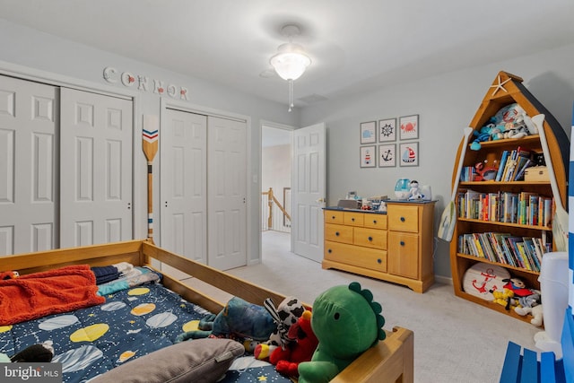 bedroom featuring light carpet and multiple closets