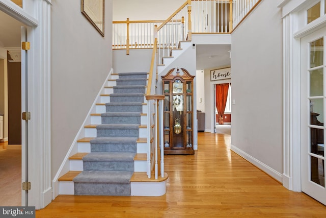 staircase with hardwood / wood-style floors and a towering ceiling