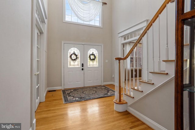 entrance foyer featuring a wealth of natural light, light hardwood / wood-style flooring, a high ceiling, and french doors