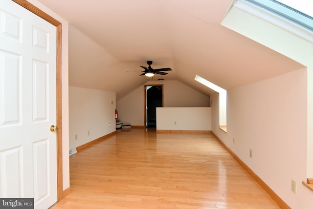 additional living space featuring ceiling fan, light wood-type flooring, and lofted ceiling with skylight