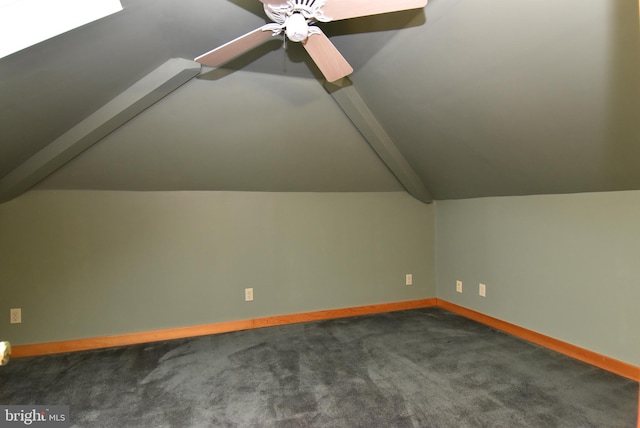 additional living space with ceiling fan, vaulted ceiling with beams, and dark colored carpet