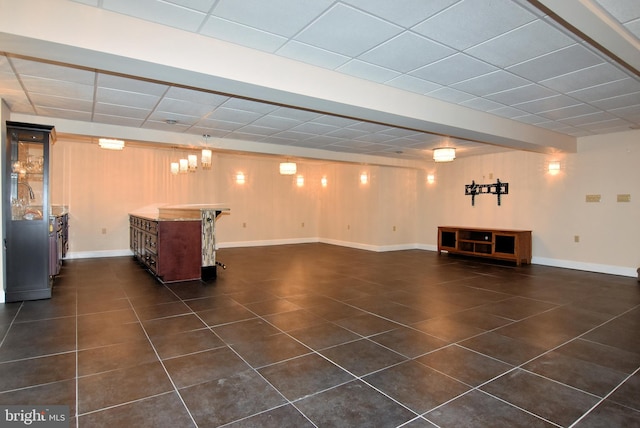 basement with a drop ceiling and dark tile patterned floors