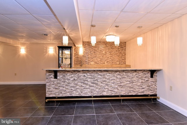 bar featuring pendant lighting, dark tile patterned flooring, and a paneled ceiling