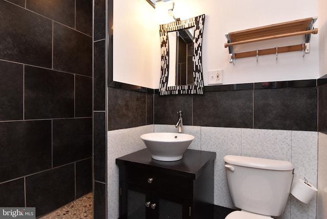 bathroom with tile walls, vanity, and toilet