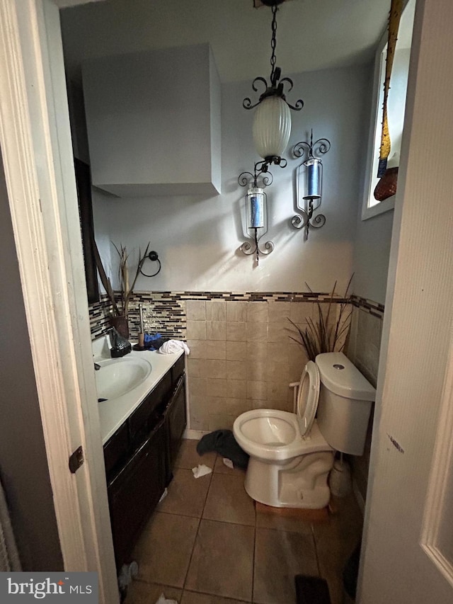 bathroom with tile walls, vanity, toilet, and tile patterned floors