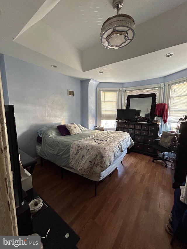 bedroom with a tray ceiling and hardwood / wood-style floors