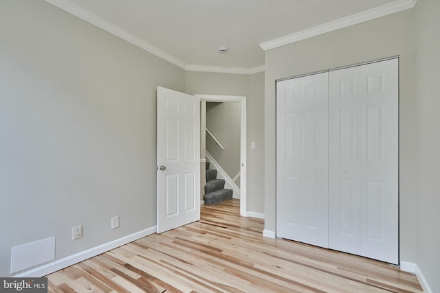 unfurnished bedroom with light hardwood / wood-style flooring, a closet, and ornamental molding