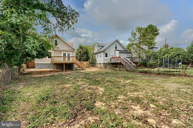 view of yard featuring a trampoline and a wooden deck