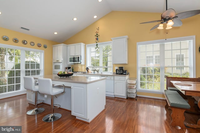 kitchen featuring white appliances, plenty of natural light, a kitchen island, and white cabinets