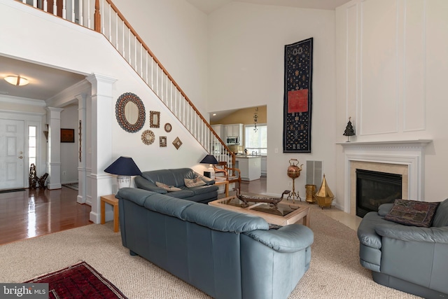 living room with ornate columns, crown molding, high vaulted ceiling, and hardwood / wood-style floors