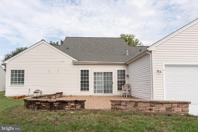 rear view of house with a patio area, a lawn, and a garage