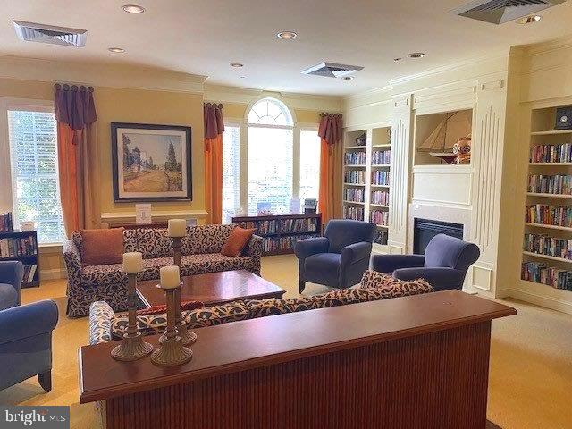 carpeted living room featuring ornamental molding, a healthy amount of sunlight, and built in shelves