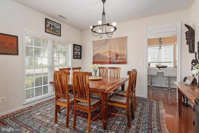 dining room with an inviting chandelier and dark wood-type flooring