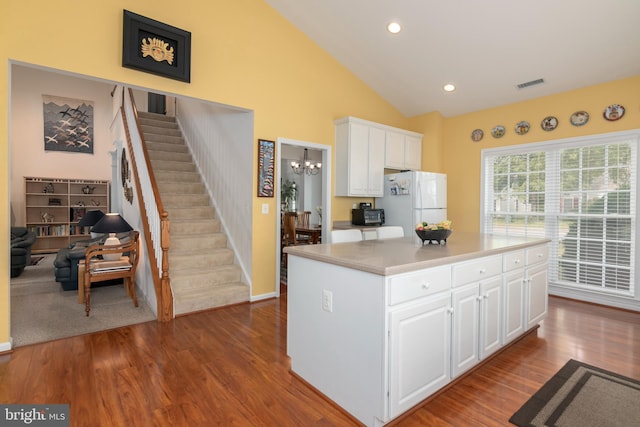 kitchen with white cabinetry, light wood-type flooring, white refrigerator, and a kitchen island