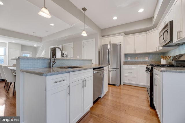 kitchen featuring appliances with stainless steel finishes, hanging light fixtures, and white cabinetry